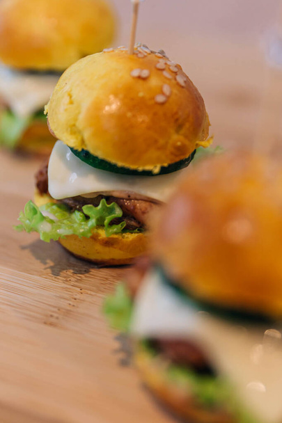 Tři lahodné kuřecí sýr hamburgery na dřevěné desce - Fotografie, Obrázek