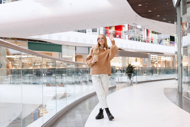 a woman greets someone in a shopping mall - Foto, Imagen