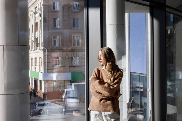 blonde thought by the window overlooking the city - Photo, Image