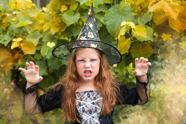 Halloween. pequeña bruja alegre con una varita mágica y el libro evoca y ríe. - Foto, Imagen