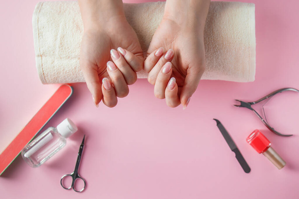 Procedimiento de spa para el cuidado de uñas en un salón de belleza. Manos y herramientas femeninas para manicura sobre fondo rosa. Concepto de cuidado del cuerpo. - Foto, Imagen