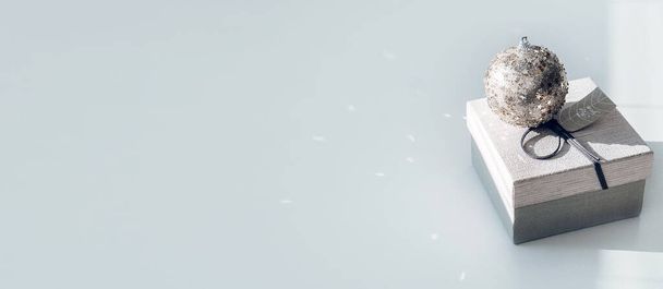 Kerstmis minimale web banner met kerst ornament bal en geschenkdoos op lichte achtergrond. Kerst geschenkdoos en schittert Kerstmis ornament bal op witte achtergrond. Vakantiebanner - Foto, afbeelding