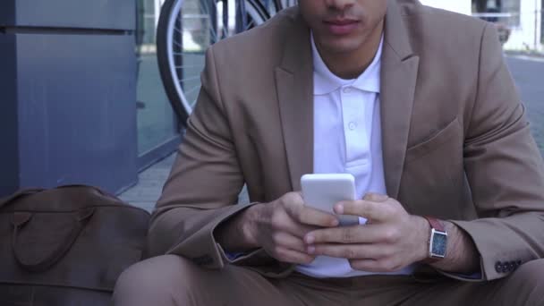 rajattu näkymä nuori liikemies messaging älypuhelimeen ulkopuolella - Materiaali, video