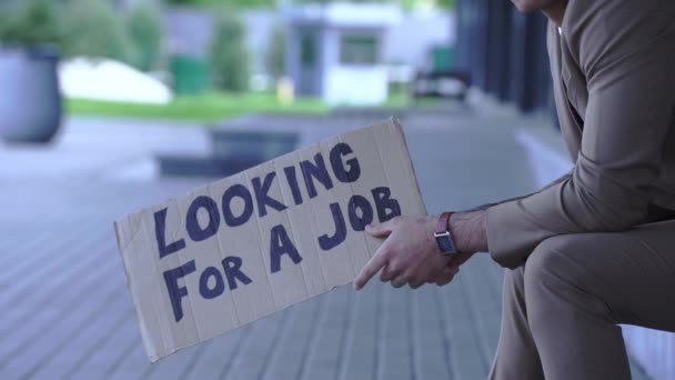 vista recortada del hombre sosteniendo cartón con la búsqueda de un trabajo de letras fuera - Imágenes, Vídeo