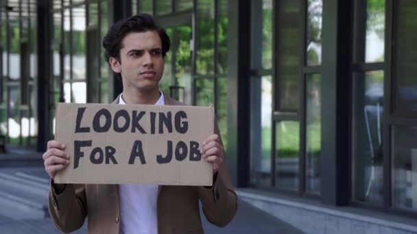 despedido hombre sosteniendo cartón con la búsqueda de un trabajo letras fuera - Imágenes, Vídeo