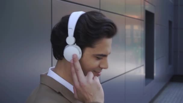 giovane uomo sorridente mentre ascolta musica in cuffie wireless  - Filmati, video