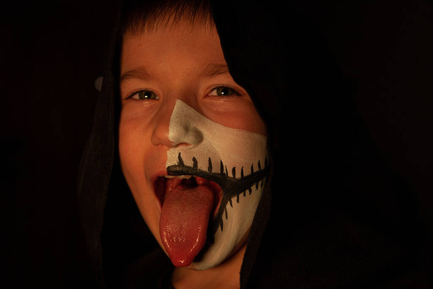 Niño con una máscara de Halloween en la oscuridad. Enfoque suave en la cara - Foto, imagen