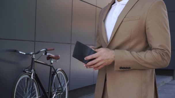 cropped view of man in suit giving money and taking paper bag near bicycle  - Footage, Video