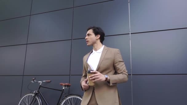 ανήσυχος άνθρωπος με κοστούμι κρατώντας χάρτινο κύπελλο και το φάκελο, ενώ περιμένει έξω  - Πλάνα, βίντεο