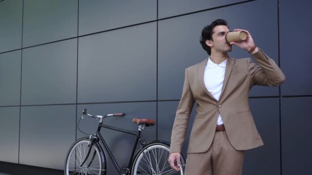 allegro uomo d'affari in giacca e cravatta bere caffè per andare a controllare il tempo fuori  - Filmati, video