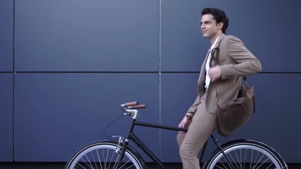 jovem empresário de terno pendurado pasta de couro e andar de bicicleta - Filmagem, Vídeo