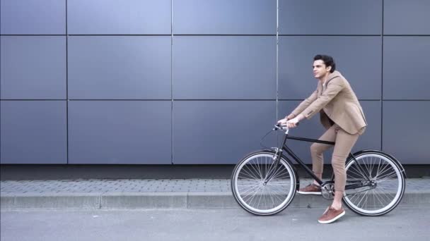 gelukkige jonge zakenman in pak zwaaien hand en paardrijden fiets - Video