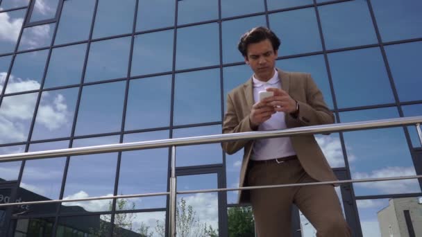 low angle view of cheerful young businessman walking and talking on smartphone - Footage, Video