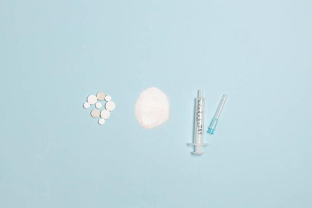 Syringe and vial on blue background. Treatment: tablets, injection. Safety at pandemic or quarantine. Complex therapy - 写真・画像
