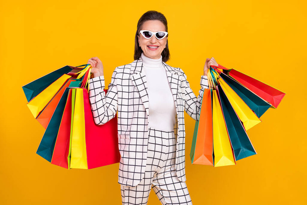 Portrait of attractive satisfied lady shopper hold packages isolated on yellow color background - Фото, зображення