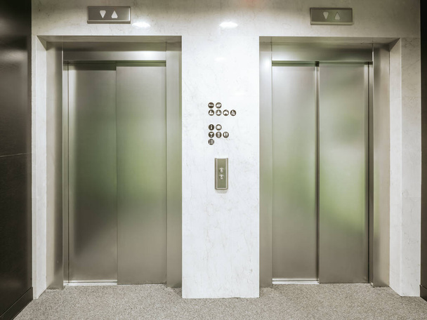 Dwie nowe windy w hotelu. Materiał jest ze stali nierdzewnej. Pomiędzy windami są znaki podłogi i przyciski wywołujące windę. - Zdjęcie, obraz