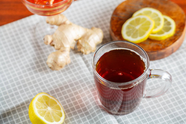 A cup of strong infused tea on a napkin next to lemon ginger jam. Horizontal photo - Foto, immagini