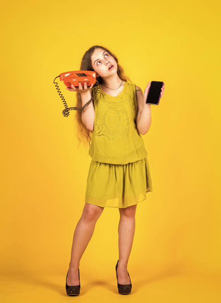 in shop. conversation and communication. teen girl with retro phone and smartphone. kid vintage fashion. happy childhood. cute child on yellow background. new technology in modern life - Φωτογραφία, εικόνα