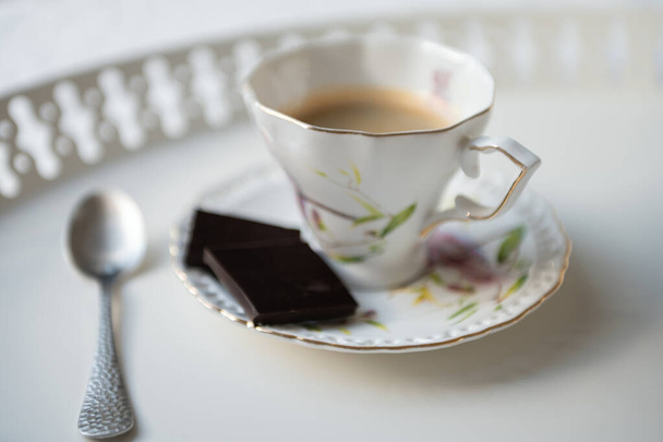 Stylowa filiżanka espresso czarna kawa z czarną czekoladą na pięknej białej tacy w stołówce - Zdjęcie, obraz