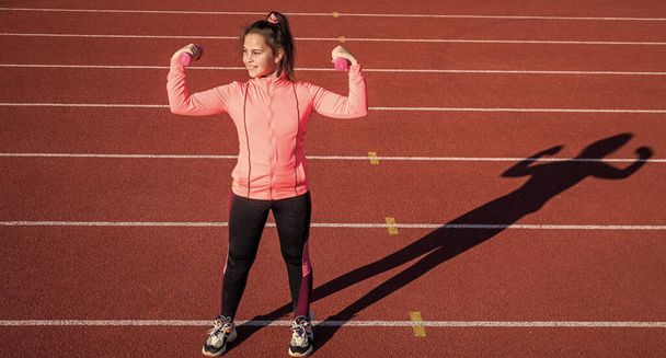 childhood development. child do exercise on track. healthy childhood. workout on fresh air outdoor. confident athlete with barbell. teen girl warming up on stadium. kid in sportswear use dumbbell - 写真・画像