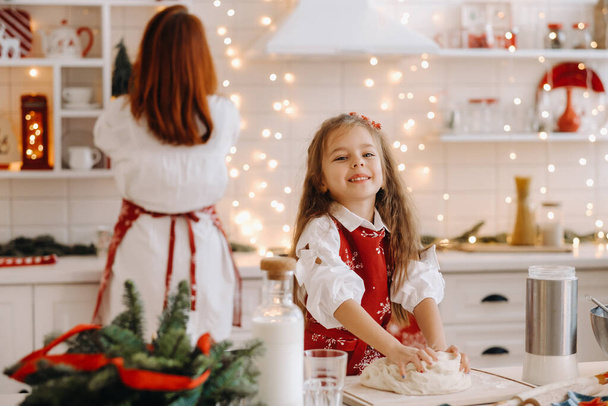 Mom and daughter in the New Year's kitchen together prepare dough for Christmas cookies. - Zdjęcie, obraz