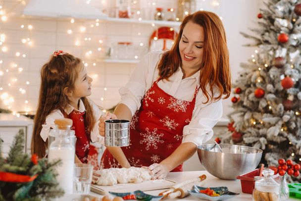Mom and daughter in the New Year's kitchen together prepare dough for Christmas cookies. - Fotó, kép