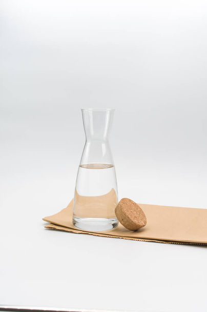 glass flask filled with pure clean water on a white and food paper background with text space - Foto, afbeelding