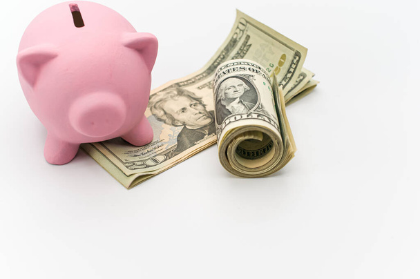a cute pink piggy bank with a banknotes wad on a white tabletop with copy space - Photo, Image