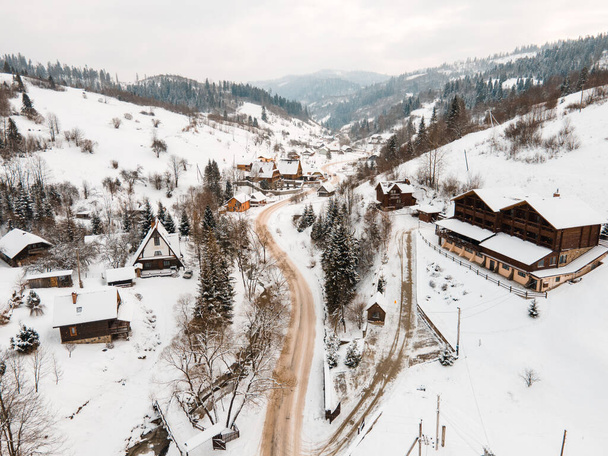 Karpatya dağlarının ortasındaki karlı köydeki hava manzaralı yol Ukrayna 'ya çıkıyor. - Fotoğraf, Görsel