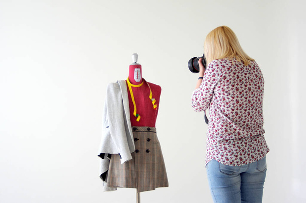 A blonde female photographer taking pictures of a mannequin with a skirt and a suit jacket - Foto, Imagen