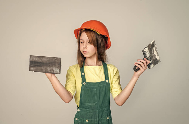 lets start. renovation and repair. using working tool. teen girl in helmet and boilersuit with spatula. child wear hard hat. kid builder on construction site. worker engineer. architect in workshop - Fotografie, Obrázek