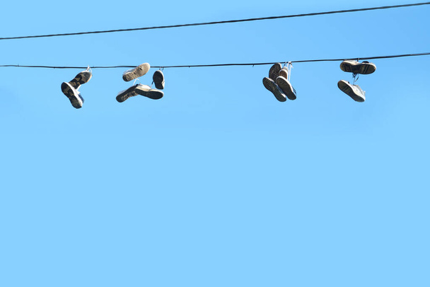 Sports shoes are hanging on wires.Sneakers suspended by laces on electrical wires - Fotografie, Obrázek