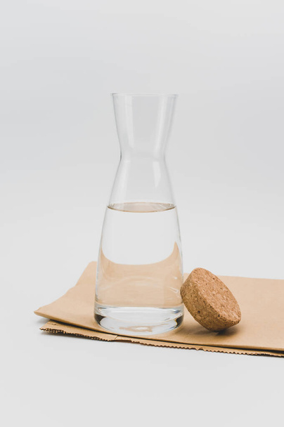 glass flask filled with pure clean water on a white and food paper background with text space - Zdjęcie, obraz