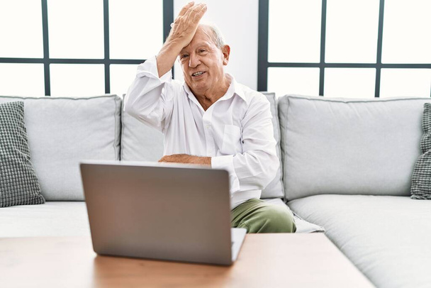 Vanhempi mies, joka käyttää kannettavaa tietokonetta kotona istuu sohvalla yllättyneenä kädestä päähän virheestä, muista virhe. unohdettu, huono muisti käsite.  - Valokuva, kuva
