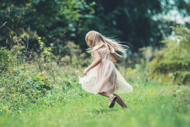 Little girl spinning around, dancing  outdoors in the forest - Photo, Image