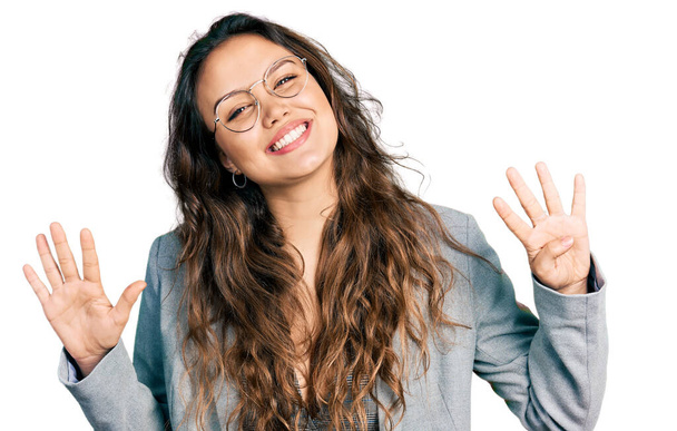 Menina hispânica jovem vestindo roupas de negócios e óculos mostrando e apontando para cima com os dedos número nove, sorrindo confiante e feliz.  - Foto, Imagem