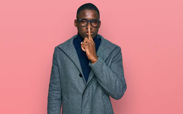 Νεαρός Αφροαμερικάνος που φοράει επαγγελματικά ρούχα και γυαλιά ζητώντας να είναι ήσυχος με τα δάχτυλα στα χείλη. σιωπή και μυστική έννοια.  - Φωτογραφία, εικόνα