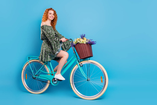 Full length profile photo of sweet ginger hairdo lady ride bike wear dress sneakers isolated on blue color background - Foto, Bild
