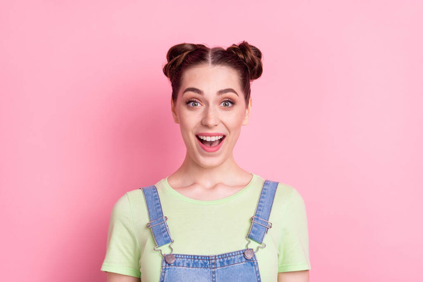 Photo portrait girl with bun smiling staring amazed isolated pastel pink color background - Φωτογραφία, εικόνα