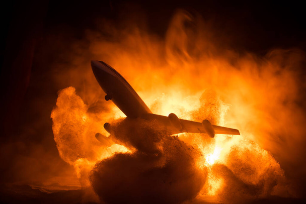 Air Crash. Burning falling plane. The plane crashed to the ground. Decorated with toy at dark fire background. Air accident concept. Selective focus - Фото, изображение