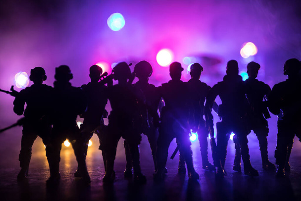 Bereitschaftspolizisten signalisieren Bereitschaft. Machtkonzept der Regierung. Die Polizei ist im Einsatz. Rauch auf dunklem Hintergrund mit Lichtern. Blaurote blinkende Sirenen. Selektiver Fokus - Foto, Bild