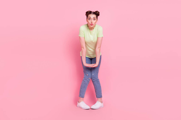 Photo of cute adorable affectionate girl shy send air kiss wear green t-shirt jeans sneakers isolated on pink background - Photo, image