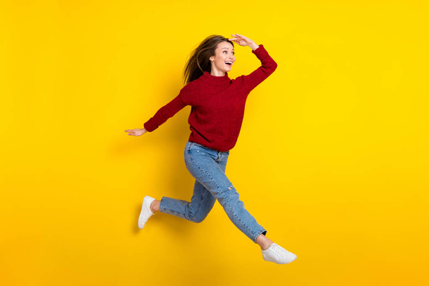 Full length body size view of attractive amazed cheerful girl jumping walking searching news isolated over bright yellow color background - Фото, изображение