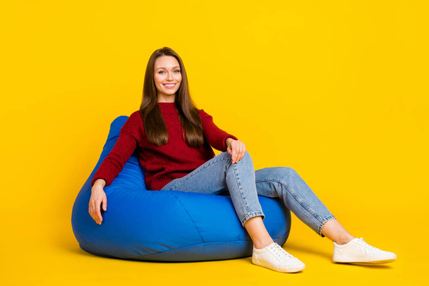 Full size photo of sweet young lady sit on bag wear sweater jeans isolated on vivid yellow color background - Fotó, kép