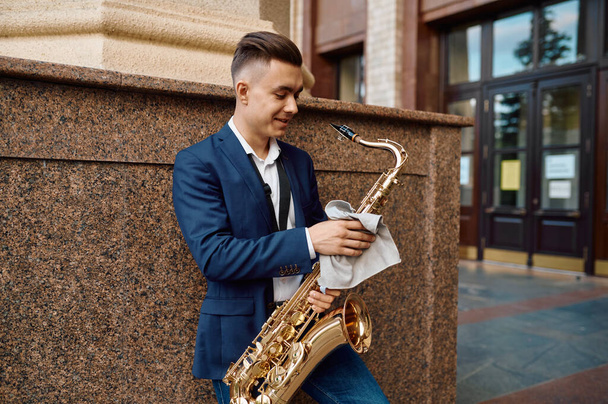 Mężczyzna saksofonista pozuje z saksofonem w budynku - Zdjęcie, obraz