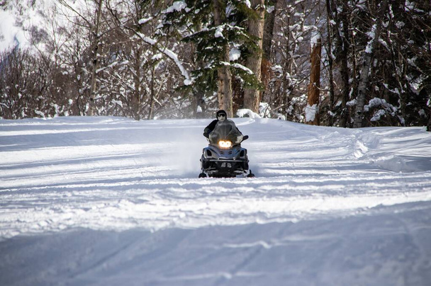 paseos en moto de nieve negro en un camino nevado en las montañas - Foto, imagen