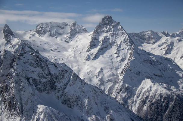 schneebedeckte Berge Gipfel in den Wolken blauer Himmel Kaukasus - Foto, Bild