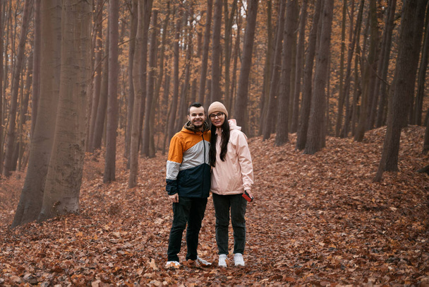 Fiatal pár az őszi erdőben. Férfi és nő kapcsolatban vannak, akik jól érzik magukat a szabadban - Fotó, kép