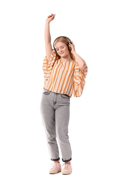 Молодая блондинка в наушниках слушает музыку на белом фоне - Фото, изображение