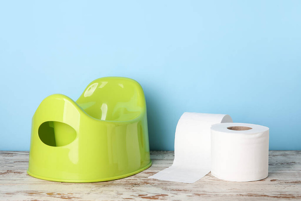 Rolos de papel higiênico e potty modernos no chão de madeira perto da parede de cor - Foto, Imagem